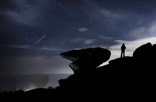 Ein Mann beobachtet einen Meteor über der Felsformation Brimham Rocks während des Geminiden-Meteoritenschauers. Foto: picture alliance/dpa/PA Wire/Danny Lawson