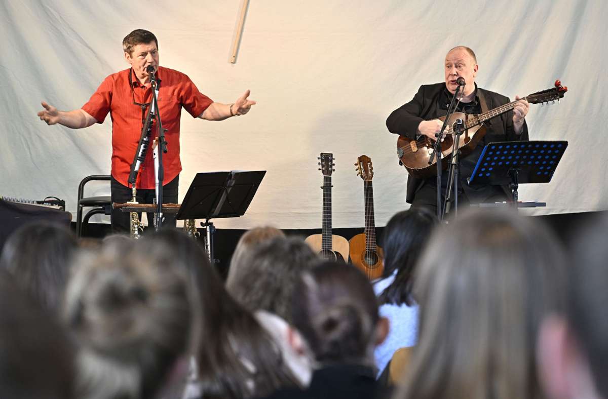 Kokott & Georgi mit zwei Gitarren, einem Mandoloncello, drei Saxophonen, zwei Querflöten, einer  „Low whistle“ und einer „Zauberflöte“ auf der Bühne in der Schulaula. Foto: /Heiko Matz