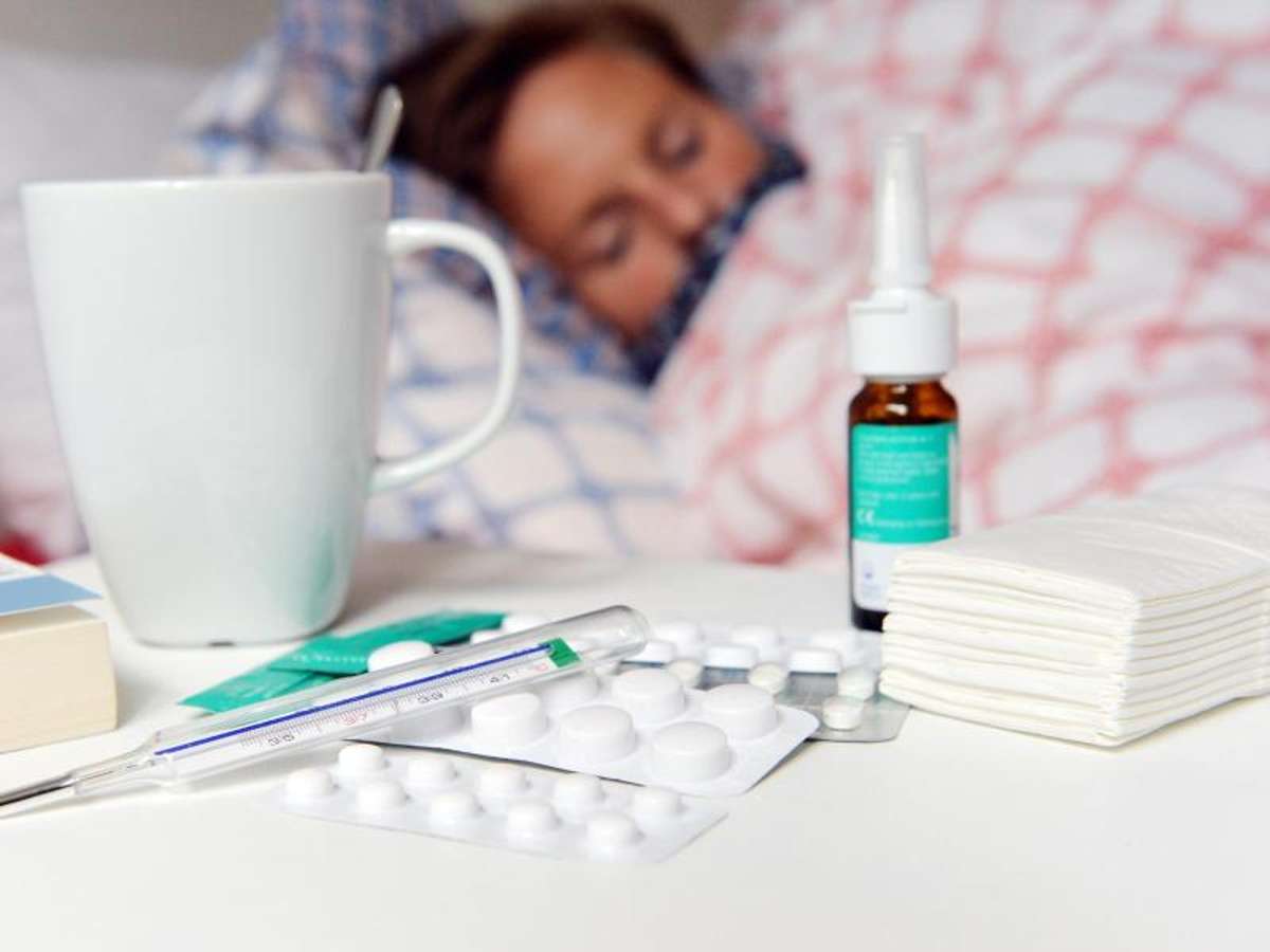 Medikamente und ein Fieberthermometer liegen auf einem Nachttisch. Foto: Maurizio Gambarini/dpa/Illustration