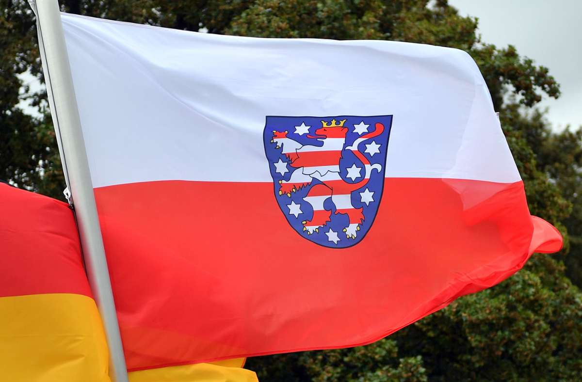 Eine Fahne mit den Farben und dem Wappen Thüringens. Foto: dpa/Martin Schutt