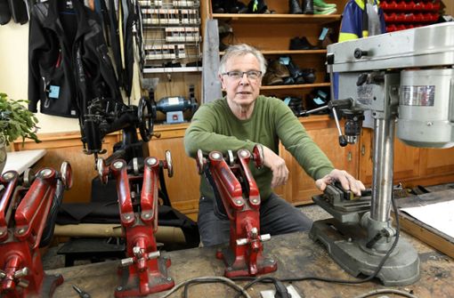 Rolf Schwämmlein in seiner Werkstatt. Die roten Maschinenarme an die er sich lehnt, dienen zum Ausweiten der Schuhe. Foto: Carl-Heinz Zitzmann