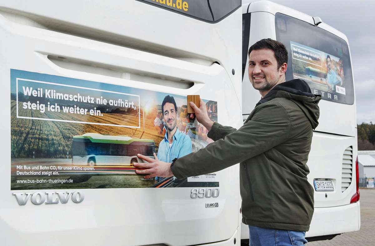 Marcel Will beklebt das Heck einen Linienbusses mit Klimawerbung. Foto: Michael Bauroth