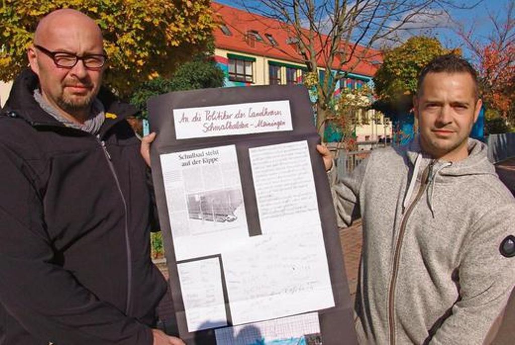 Kai Christ (links) und Michael Storch mit dem Plakat, das die Grundschüler für den Erhalt des Bades gestaltet und ihnen übergeben haben. 	Fotos (2): Schunk
