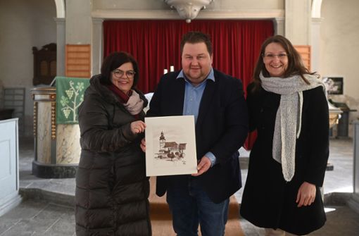 Andrea Sokoll (links) und Melanie Angermüller freuen sich über ein malerisches Geschenk von Heldburgs Bürgermeister Christopher Other für ihre Kirchgemeinde. Foto:  