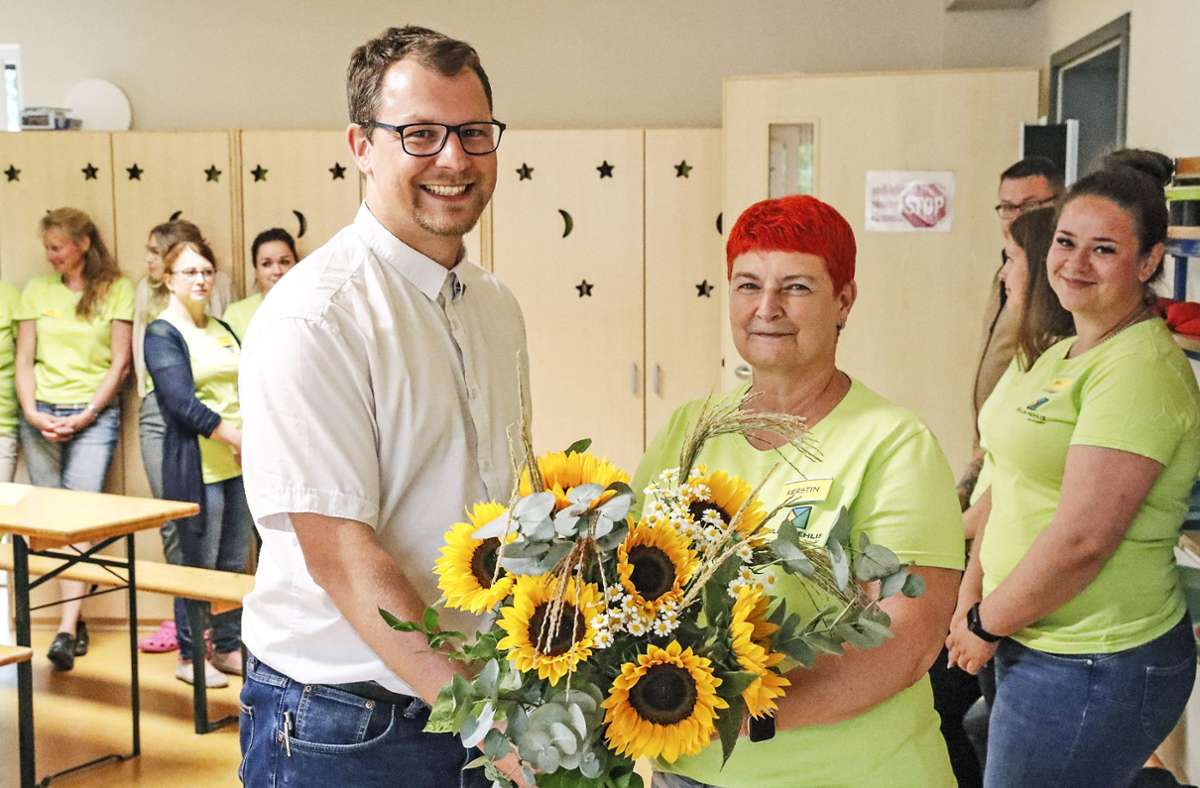 Blumen dürfen nicht fehlen zum Geburtstag. Kindergartenleiterin Kerstin Backhaus nimmt die Glückwünsche stellvertretend fürs gesamte Team vom zweiten Beigeordneten der Stadt, Thomas Bischof, entgegen.