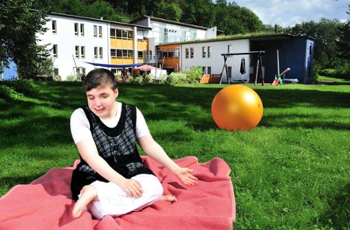 Franziska, eine Klientin des Wohnbereichs für Erwachsene, sitzt im Garten; im Hintergrund ist das Kniese-Hause zu sehen. Dort leben die Kinder und Jugendlichen. Foto: Blindeninstitut Thüringen